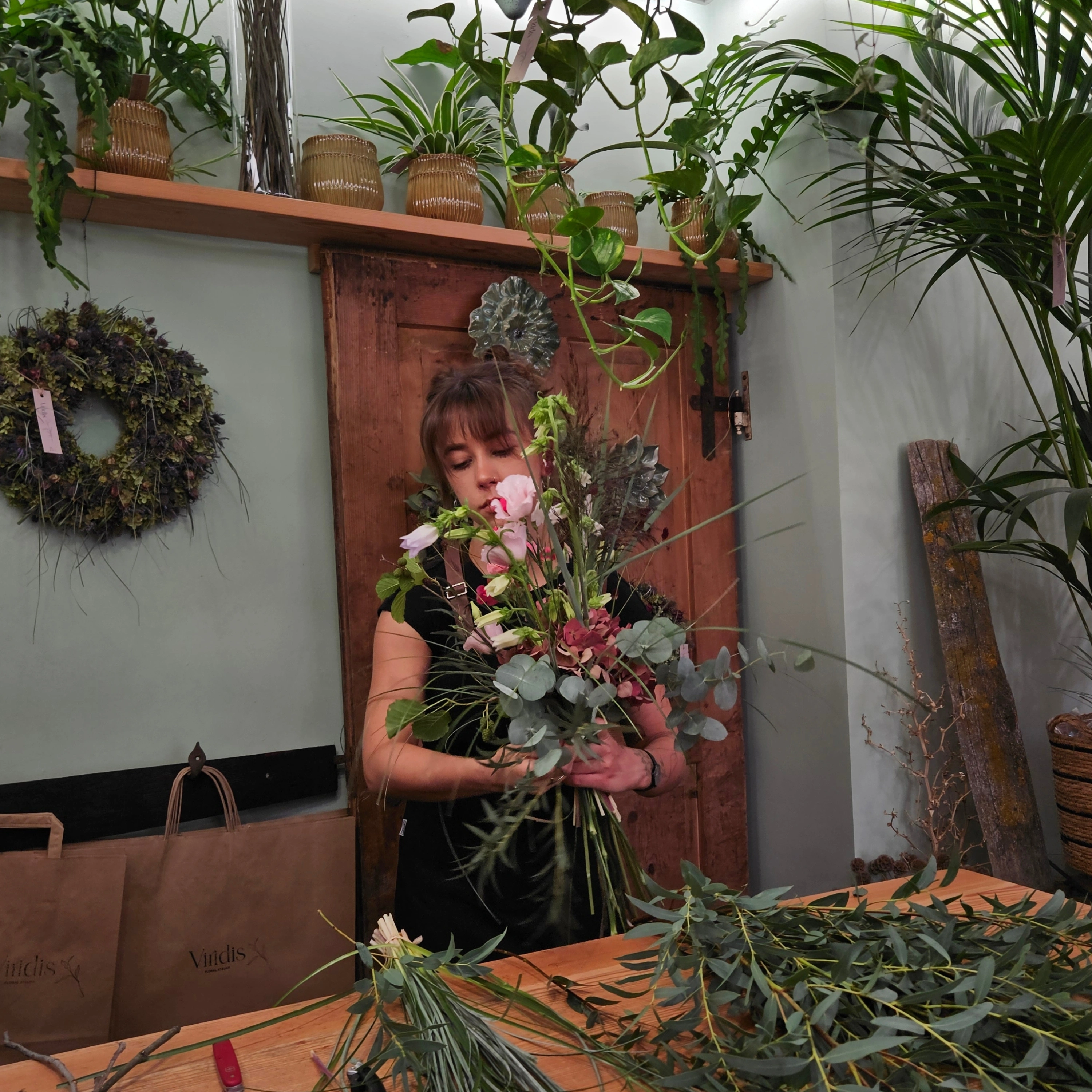 Cosima compone un bouquet con fiori rosa ed eucalipto nel Viridis Floral Atelier